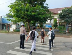 Personel Sat Lantas Polres Bima Kota Bantu Anak Sekolah Menyeberang Jalan